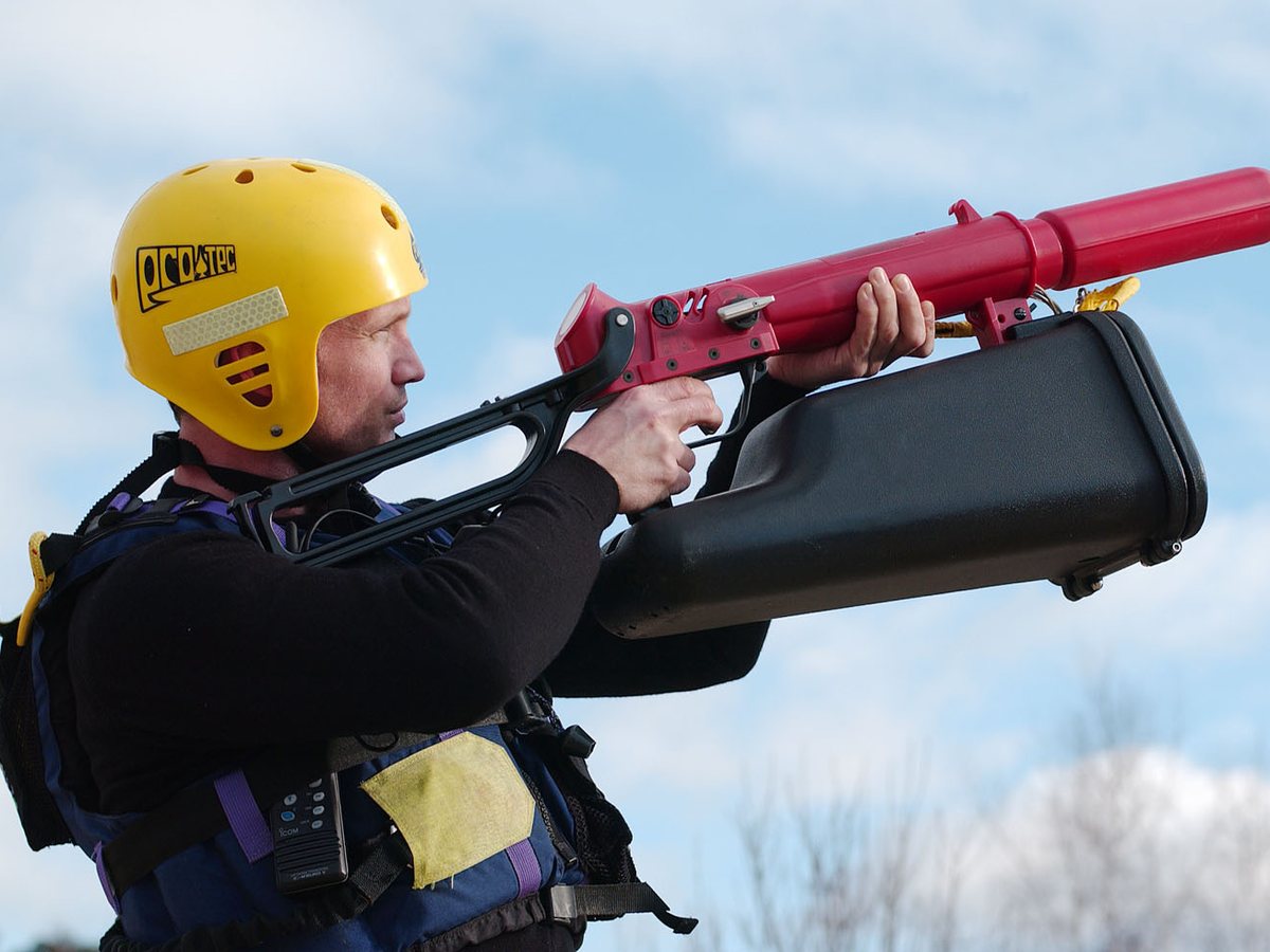 Rescuer in a helmet and PFD aiming a ResQmax line thrower