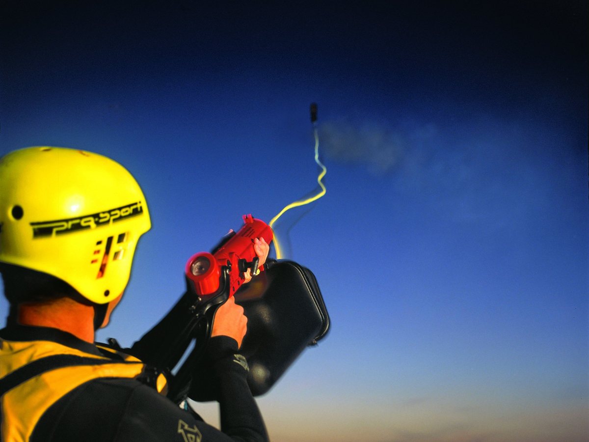 Rescuer firing a ResQmax line out to sea at dusk