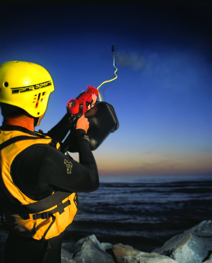Rescuer on a rocky shore firing a ResQmax line out to sea at dusk