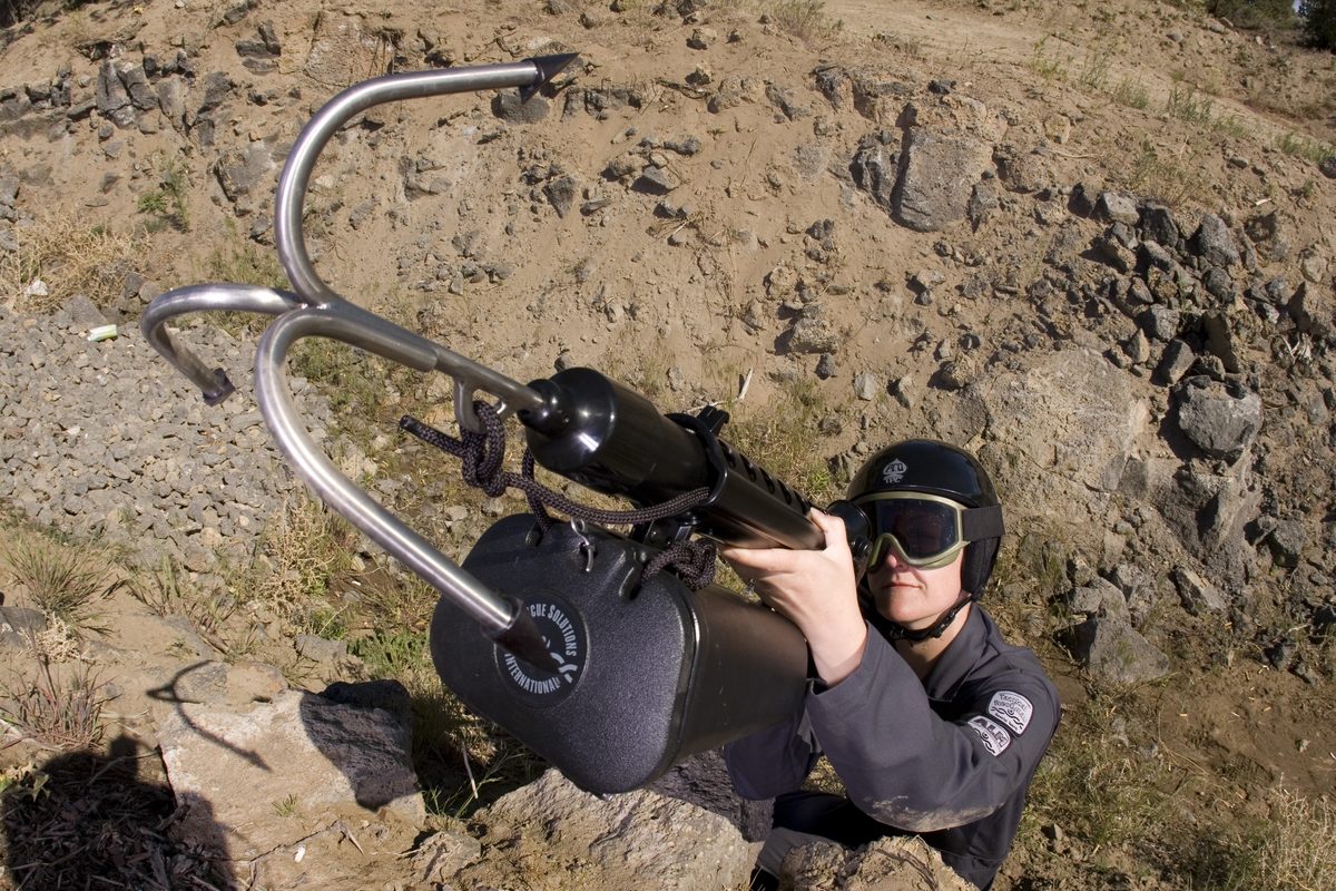 Operator aiming a Tactical ResQmax with grappling hook up a rocky slope